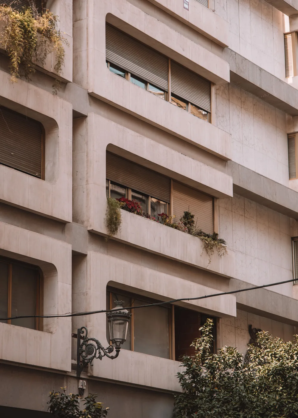 Detalle de fachada residencial renovada con balcones y vegetación